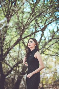 Young woman standing against trees in forest