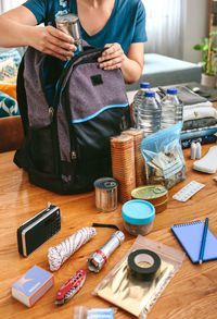 Woman putting cans of food to prepare emergency backpack