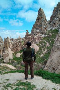 Full length rear view of man standing on rock against sky