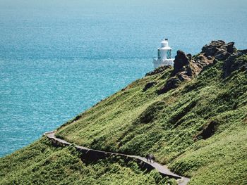 Lighthouse amidst sea and buildings against sky
