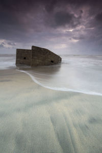 Abandoned boat on beach against sky