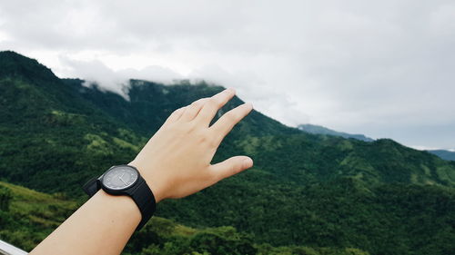 Close-up of human hand against mountain