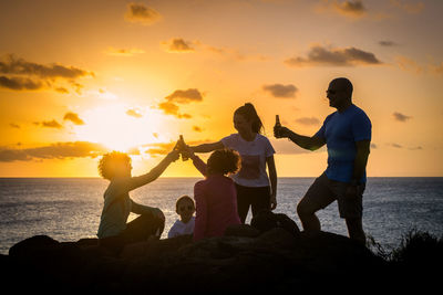 Happy family toasting at beach during sunset