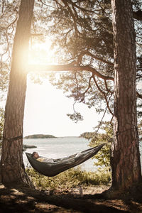 Man sleeping in hammock at lakeshore