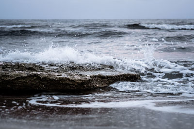 Waves splashing on shore against sky