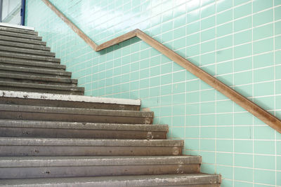 Railing on turquoise wall by steps in subway