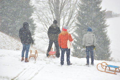 Rear view of people walking on snowed landscape