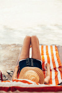 Low section of woman lying on sand at beach