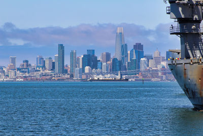 Sea by modern buildings against sky in city