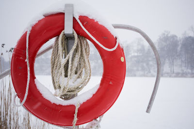 Close-up of life belt hanging on pole with rope during winter