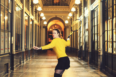 Full length portrait of woman standing in corridor of building