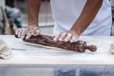 Midsection of chef rolling dough