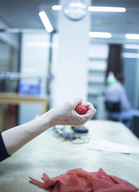 Cropped hand of person holding rubber ball on table