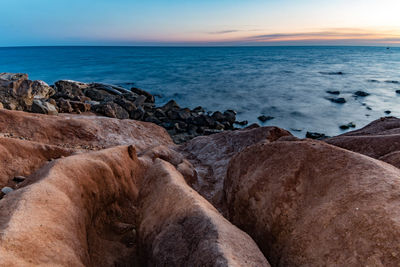 Scenic view of rocks at beach against sky