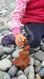 Low section of girl stacking stones