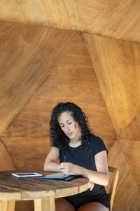 Woman using a digital tablet while sitting at a table.