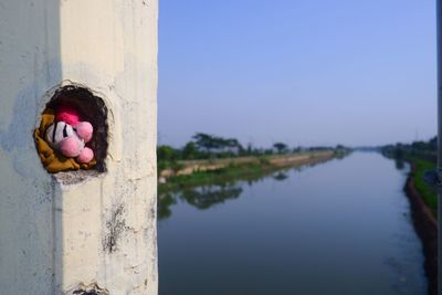 Stuffed toy by lake against sky