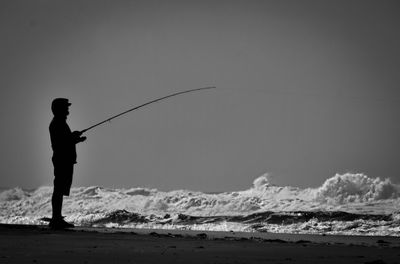 Side view of man fishing on beach