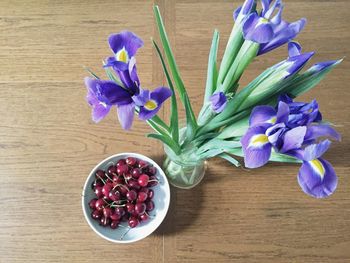 High angle view of iris flowers in vase by cherries on table