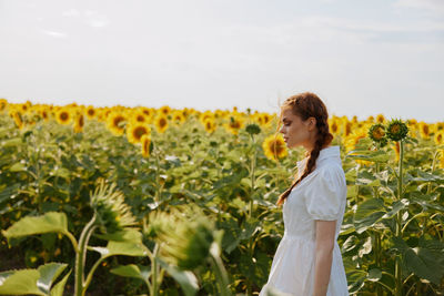 Portrait of young woman standing against plants