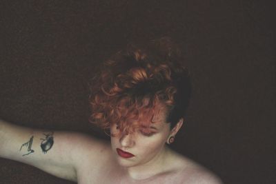 Topless woman with redhead in darkroom