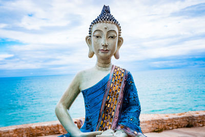 Sculpture of a meditating yogi in white clay and blue tones with the face of buddha