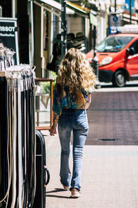 Rear view of woman standing by car in city