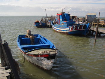 Fishing boats moored on sea against sky