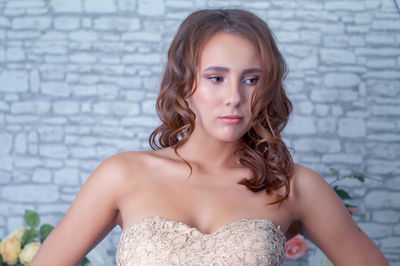 Beautiful young woman standing against wall