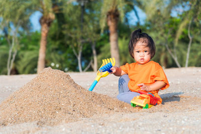 Cute girl playing in sand outdoors