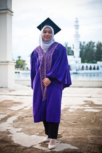 Portrait of smiling girl standing against built structure