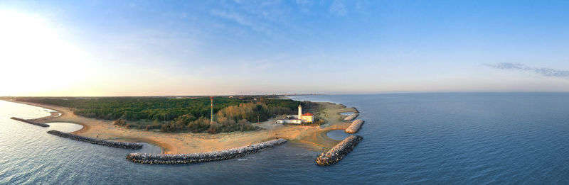 Bibione lighthouse from above at sunset in a panoramic aerial view	with sea and blue sky