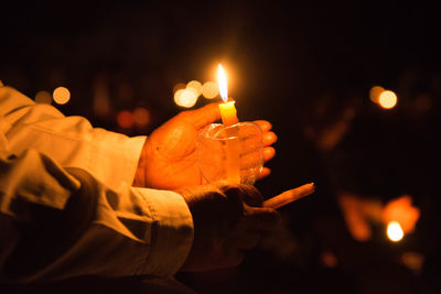 Close-up of hand shielding while holding lit candle