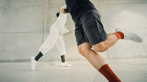 Low section of man skateboarding against wall