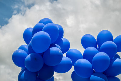 Blue balloons on cloudy sky