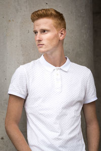 Portrait of young man standing against wall