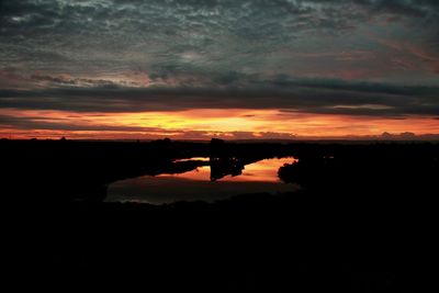 Scenic view of dramatic sky over silhouette trees during sunset