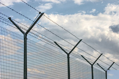 Low angle view of barbed wire fence against sky