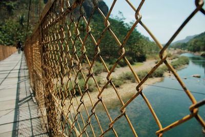 Close-up of chainlink fence by sea against sky