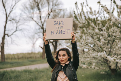 Portrait of young woman standing against plants