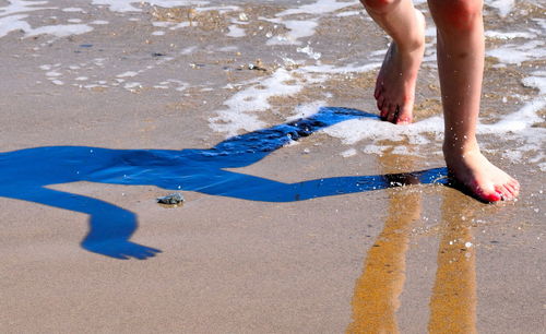 Low section of person on wet sand at beach