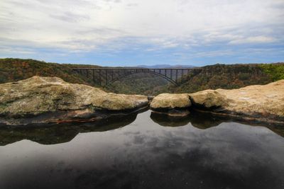 Arch bridge over river against sky