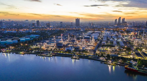 High angle view of illuminated city by river against sky