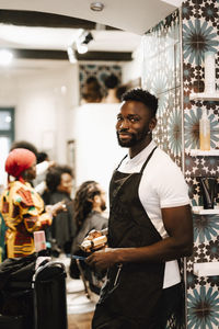 Portrait of male barber standing at hair salon