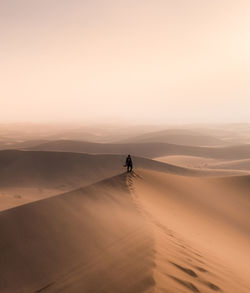 Man on desert against sky during sunset