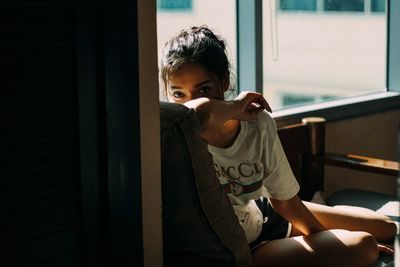 Close-up of smiling girl sitting on window