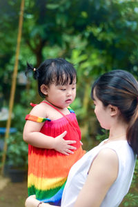 Mother carrying daughter at park