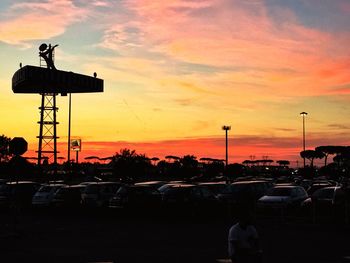 Silhouette cars against dramatic sky during sunset