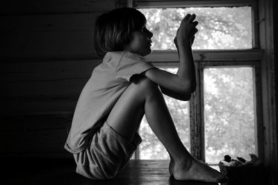 Side view of boy sitting at home