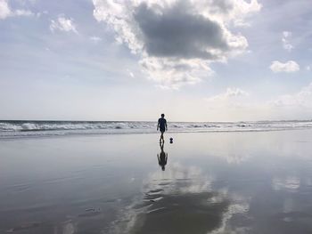 Silhouette man walking at beach against sky